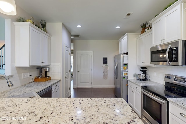 kitchen featuring appliances with stainless steel finishes, tasteful backsplash, white cabinets, and recessed lighting