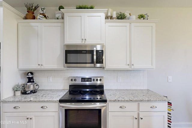 kitchen with appliances with stainless steel finishes, backsplash, white cabinets, and light stone counters