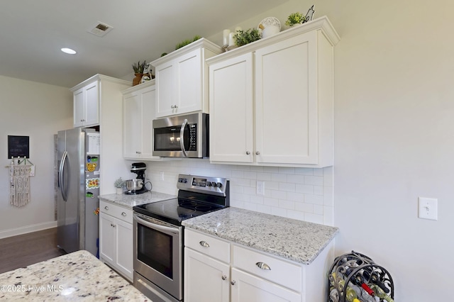 kitchen featuring appliances with stainless steel finishes, tasteful backsplash, light stone countertops, recessed lighting, and white cabinets