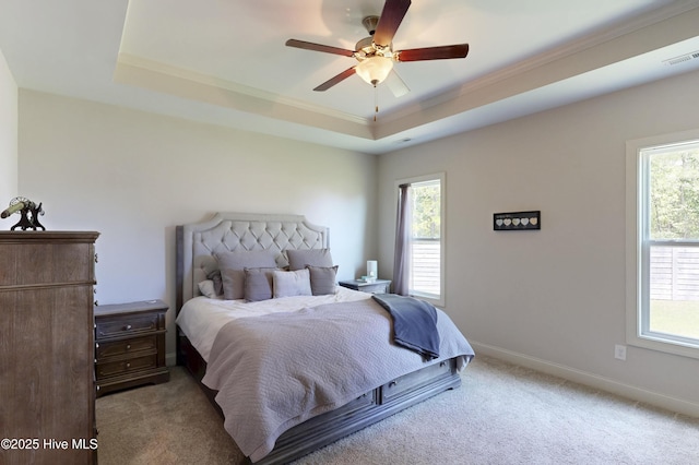 carpeted bedroom featuring ornamental molding, a raised ceiling, baseboards, and a ceiling fan