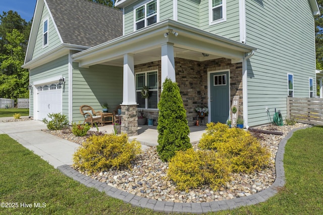 property entrance featuring an attached garage, fence, a porch, a shingled roof, and stone siding