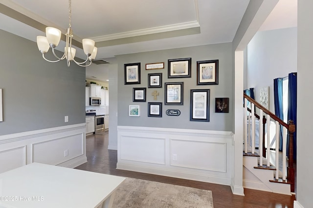 dining area with a chandelier, dark wood-type flooring, wainscoting, stairs, and a decorative wall