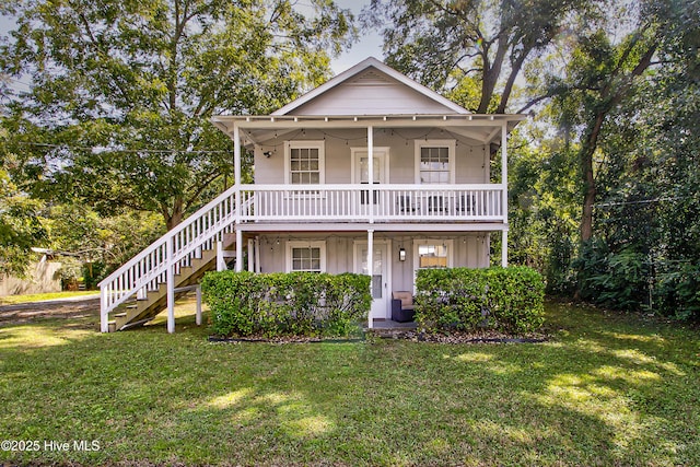 view of front of home with board and batten siding, a front yard, a porch, and stairway