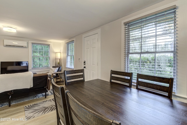 dining space featuring an AC wall unit and wood finished floors