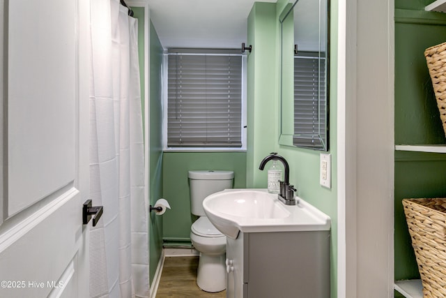 bathroom with toilet, vanity, and wood finished floors