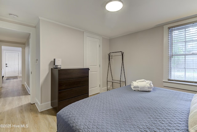 bedroom with light wood finished floors, baseboards, and ornamental molding
