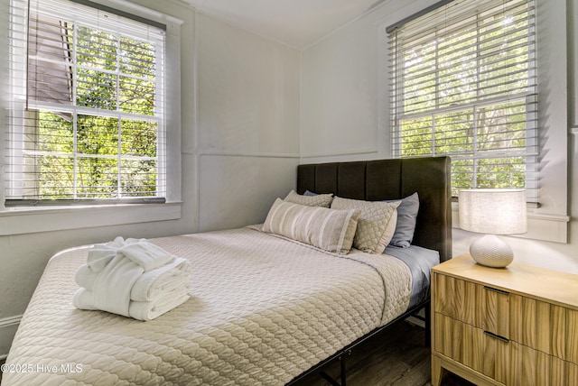 bedroom featuring multiple windows, crown molding, and wood finished floors