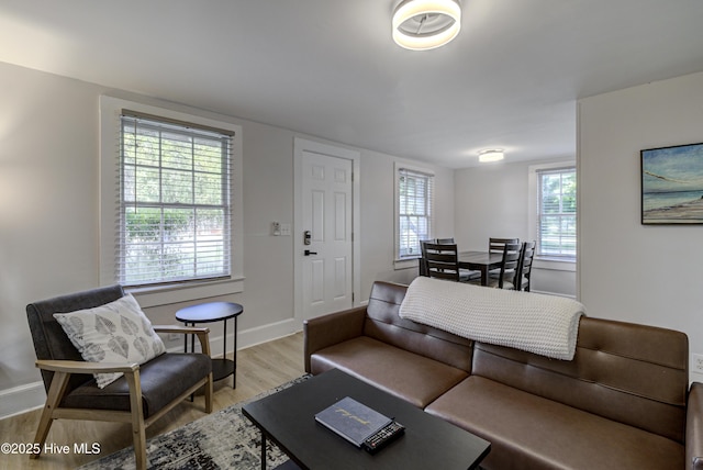 living room featuring light wood-style flooring, baseboards, and healthy amount of natural light