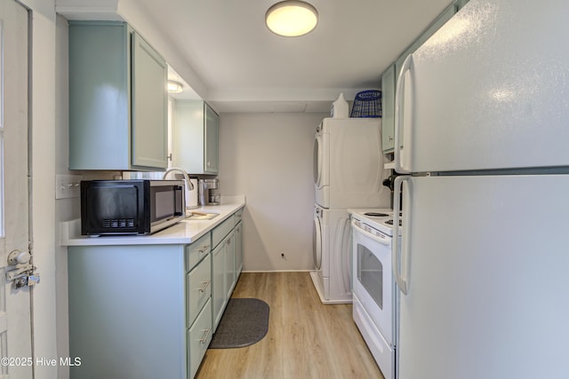 kitchen featuring white appliances, estacked washer and dryer, light wood finished floors, light countertops, and baseboards