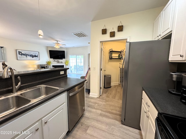 4983 Kona Ct Unit 1, Southport, NC 28461 - kitchen with appliances with stainless steel finishes, a sink, white cabinets, light wood-type flooring, and dark countertops
