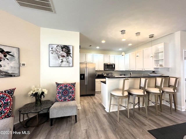 4983 Kona Ct Unit 1, Southport, NC 28461 - kitchen featuring appliances with stainless steel finishes, dark countertops, a peninsula, recessed lighting, and wood finished floors