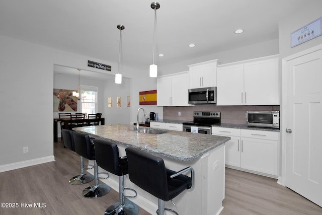 kitchen featuring stainless steel appliances, a sink, light wood-style floors, backsplash, and recessed lighting