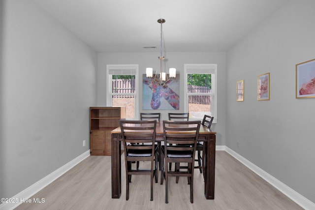 dining room with light wood finished floors, a chandelier, and baseboards