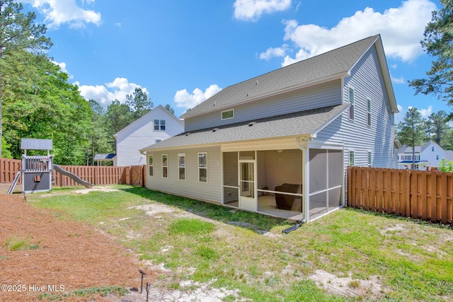 back of property featuring a sunroom, roof with shingles, and a playground