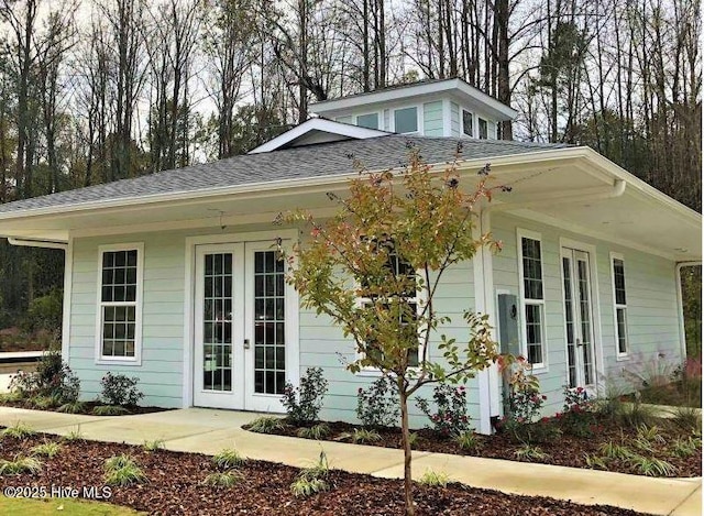 view of side of property with french doors and roof with shingles