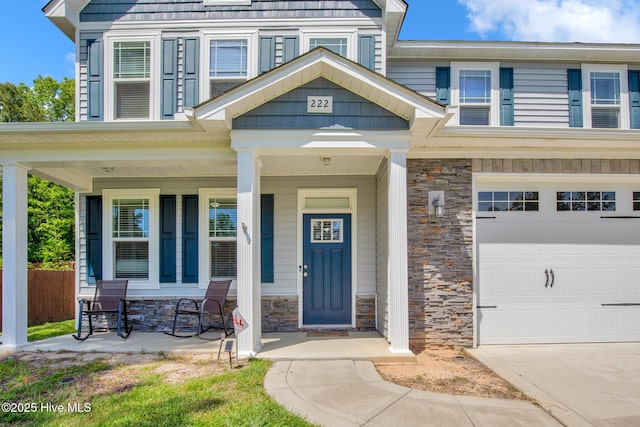 view of front of house featuring stone siding, covered porch, and fence
