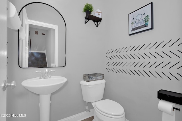 bathroom featuring toilet, baseboards, and a sink