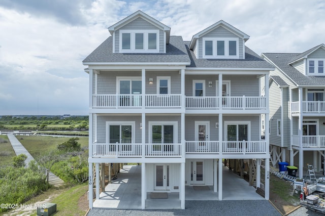 130 Sea Oaks Ct, North Topsail Beach, NC 28460 - view of front facade with driveway, a shingled roof, a balcony, and a carport