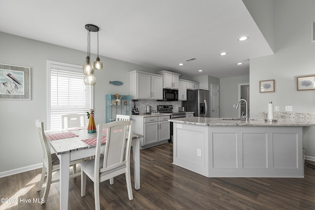 7810 Olde Pond Rd, Wilmington, NC 28411 - kitchen with stainless steel appliances, a sink, a peninsula, dark wood finished floors, and tasteful backsplash