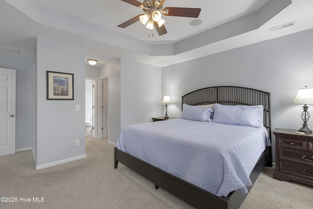 7810 Olde Pond Rd, Wilmington, NC 28411 - bedroom featuring light carpet, baseboards, connected bathroom, a tray ceiling, and a ceiling fan