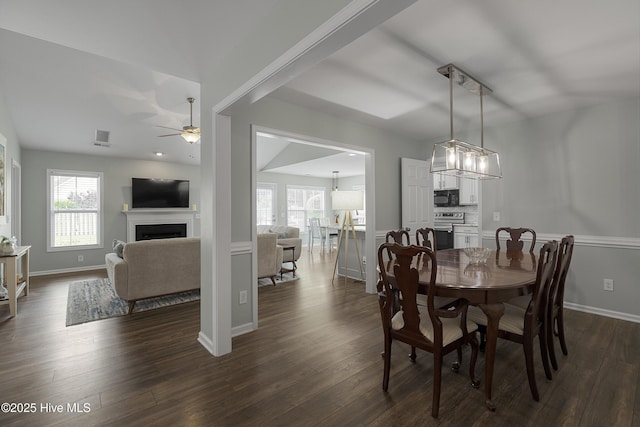 7810 Olde Pond Rd, Wilmington, NC 28411 - dining room featuring a fireplace, ceiling fan, dark wood-type flooring, and baseboards