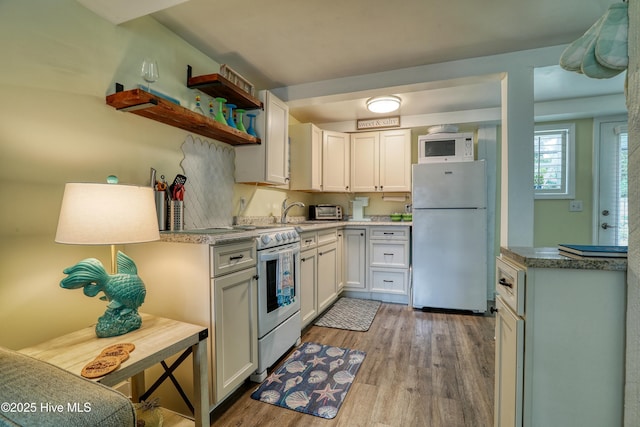 129 NE 36th St, Oak Island, NC 28465 - kitchen featuring white appliances, light wood-type flooring, light countertops, open shelves, and a sink