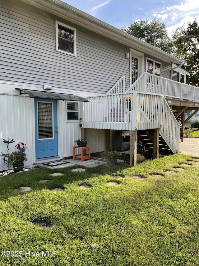 129 NE 36th St, Oak Island, NC 28465 - rear view of property with a wooden deck, stairway, a lawn, and board and batten siding