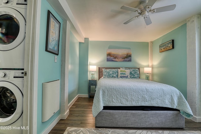 129 NE 36th St, Oak Island, NC 28465 - bedroom featuring stacked washer / dryer, dark wood-type flooring, baseboards, and a ceiling fan