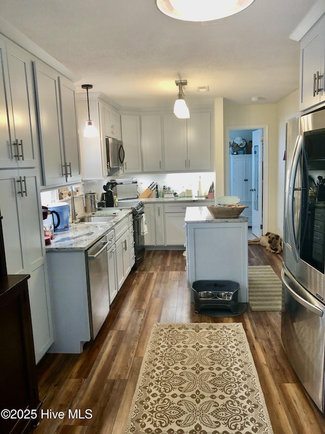 129 NE 36th St, Oak Island, NC 28465 - kitchen featuring stainless steel appliances, dark wood-style floors, light stone counters, decorative light fixtures, and white cabinets
