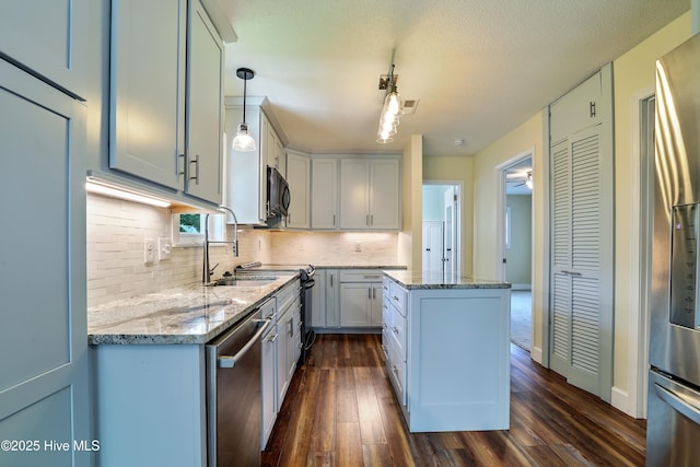 129 NE 36th St, Oak Island, NC 28465 - kitchen featuring stainless steel appliances, dark wood-type flooring, tasteful backsplash, a center island, and light stone countertops
