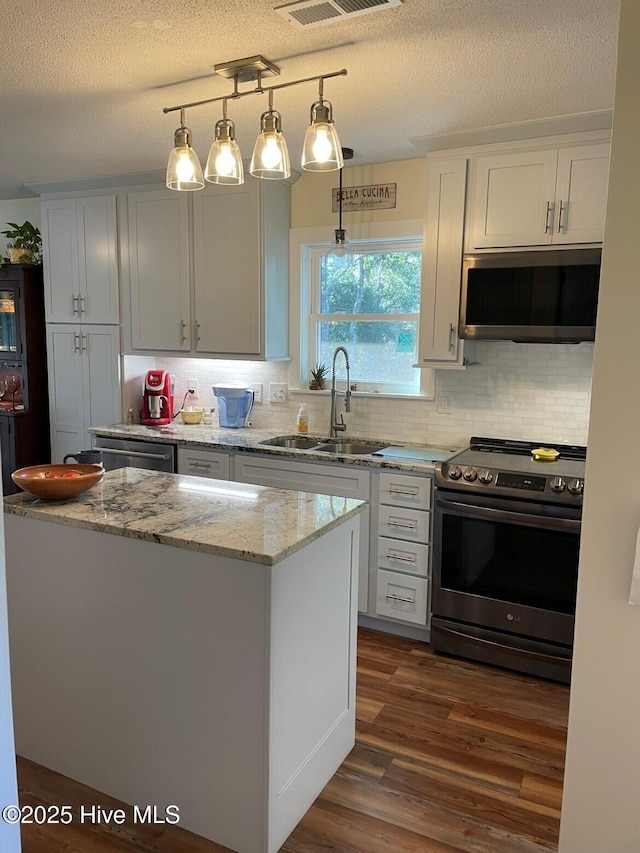 129 NE 36th St, Oak Island, NC 28465 - kitchen with stainless steel appliances, decorative backsplash, light stone countertops, dark wood finished floors, and a textured ceiling