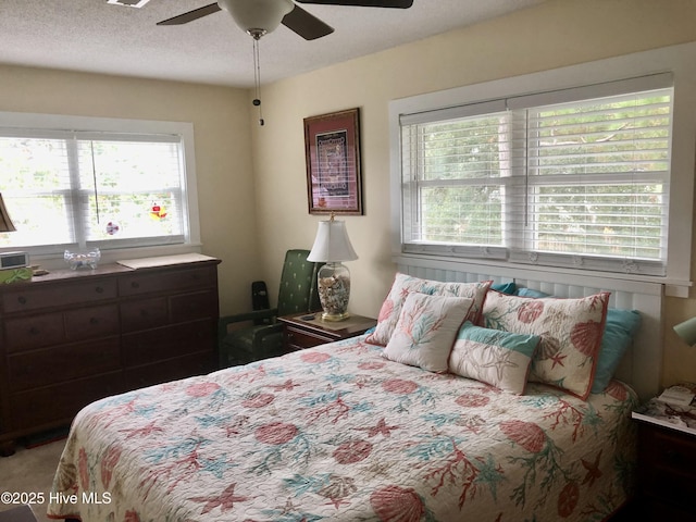 129 NE 36th St, Oak Island, NC 28465 - bedroom featuring multiple windows, a ceiling fan, and a textured ceiling