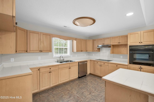 kitchen with black appliances, light brown cabinets, under cabinet range hood, a sink, and tile counters