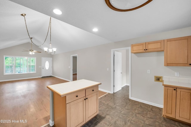kitchen featuring tile counters, light brown cabinetry, lofted ceiling, a chandelier, and baseboards