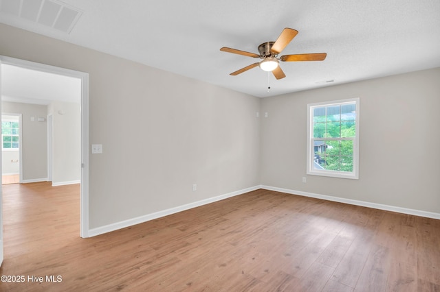 spare room featuring a ceiling fan, light wood finished floors, and baseboards
