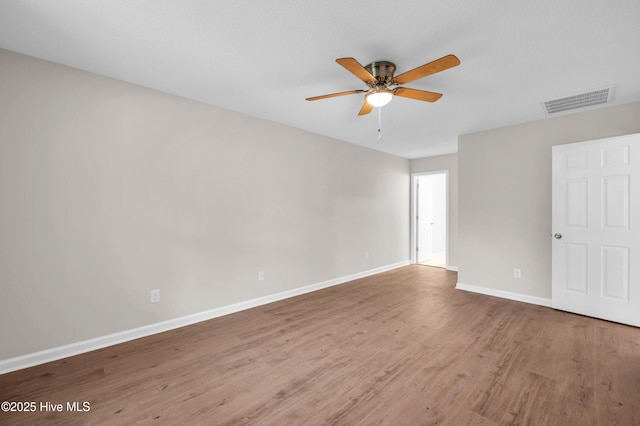 empty room featuring wood finished floors, baseboards, and a ceiling fan