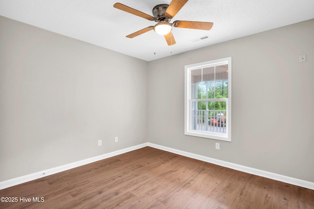spare room with baseboards, wood finished floors, and ceiling fan