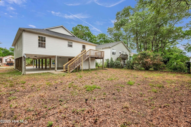 rear view of house with a carport, stairs, a wooden deck, and a shingled roof