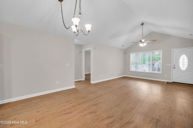 unfurnished living room featuring a chandelier, vaulted ceiling, a ceiling fan, light wood-style floors, and baseboards