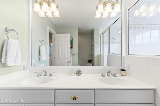 full bathroom featuring a chandelier, a shower stall, and double vanity