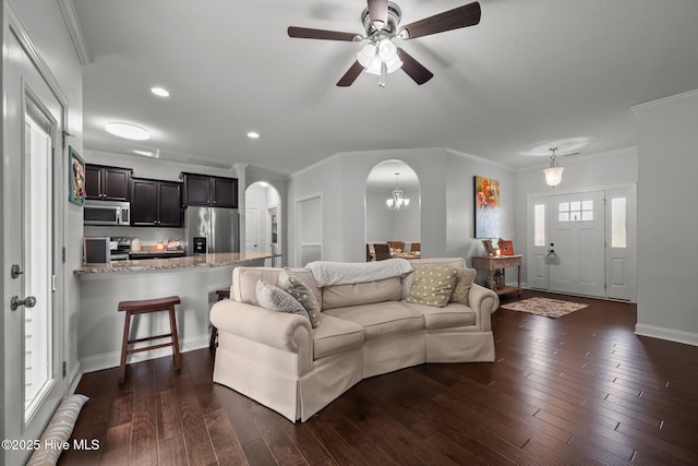living area featuring arched walkways, crown molding, dark wood finished floors, ceiling fan, and recessed lighting