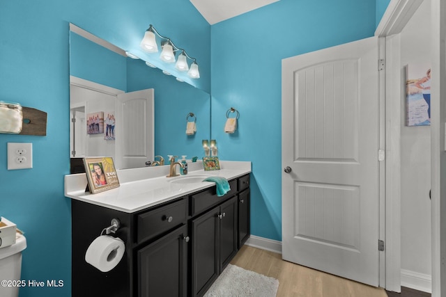 bathroom with wood finished floors, vanity, and baseboards