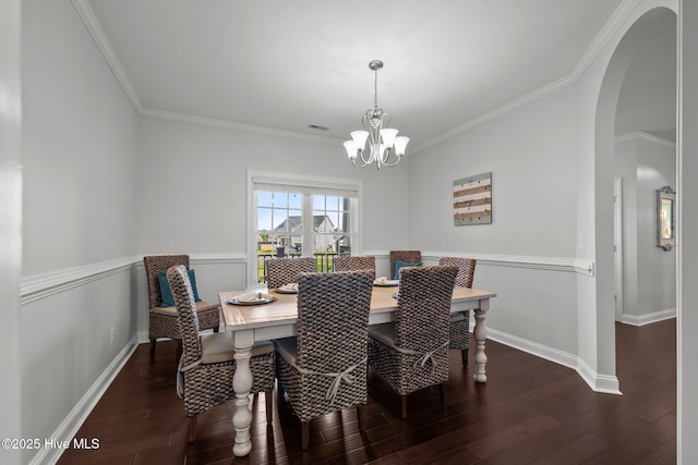 dining space with arched walkways, a chandelier, ornamental molding, wood finished floors, and baseboards