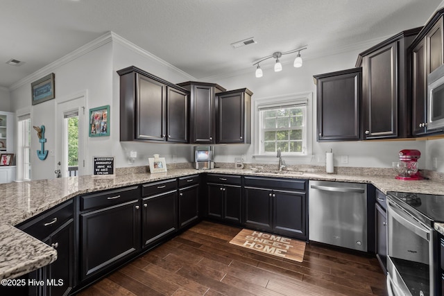 kitchen with stainless steel appliances, a sink, light stone countertops, crown molding, and dark wood-style flooring