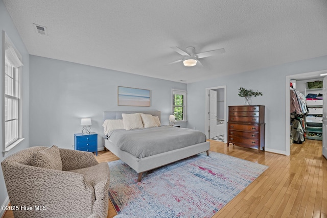 1005 Cambridge Ct, Trent Woods, NC 28562 - bedroom with a walk in closet, a textured ceiling, light wood-style floors, a closet, and ceiling fan