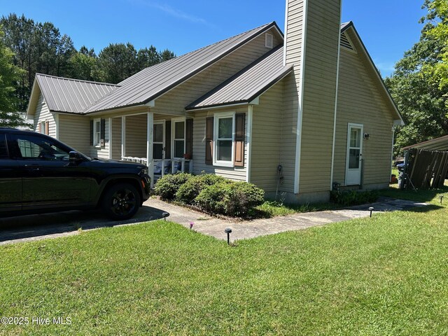 view of property exterior with a yard, metal roof, and a chimney