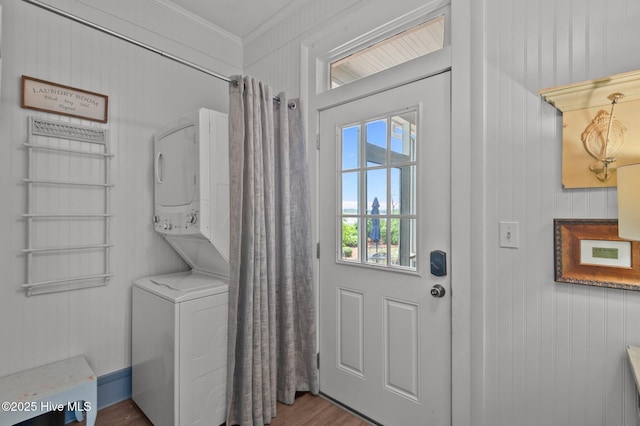 laundry area featuring stacked washer and clothes dryer, wood finished floors, and crown molding