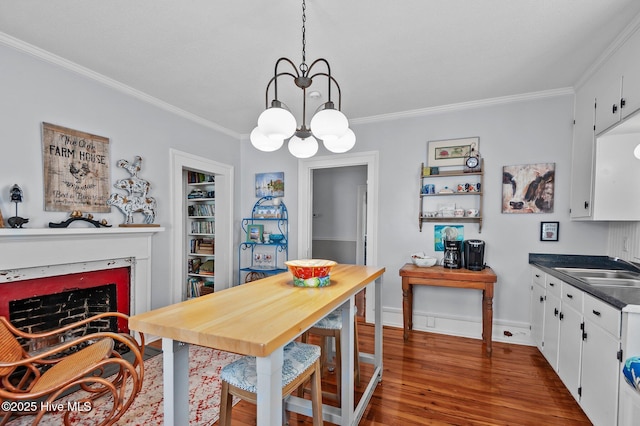 dining room with ornamental molding, a chandelier, wood finished floors, a fireplace, and baseboards