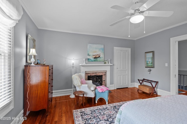 bedroom with wood finished floors, crown molding, a fireplace, baseboards, and multiple windows