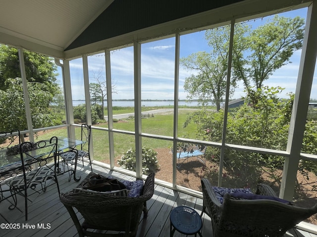 sunroom with a water view, lofted ceiling, and healthy amount of natural light